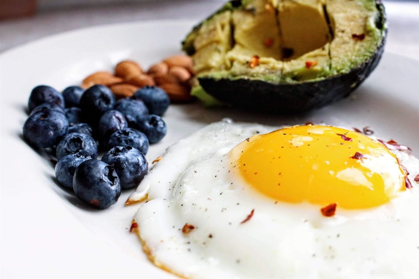 Prato com ovo frito, abacate e mirtilos, alimentos típicos da dieta cetogênica