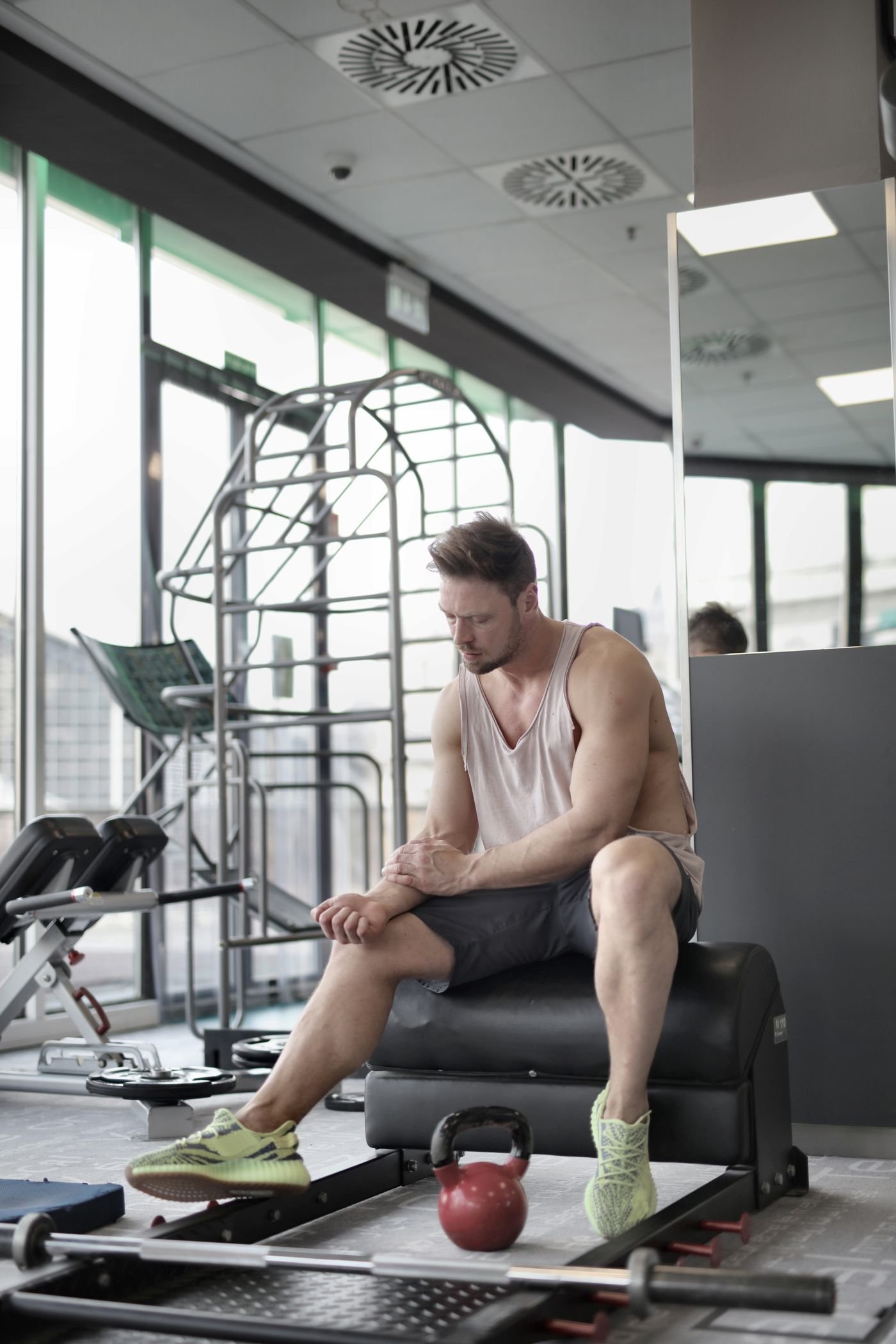 Homem sentado em banco de academia descansando durante treino de musculação
