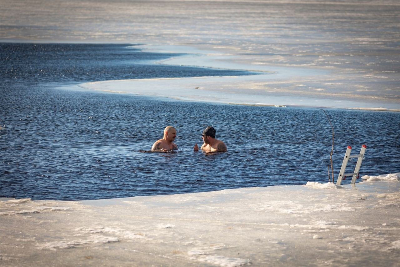 Duas pessoas praticando imersão em água gelada de um lago congelado ao ar livre