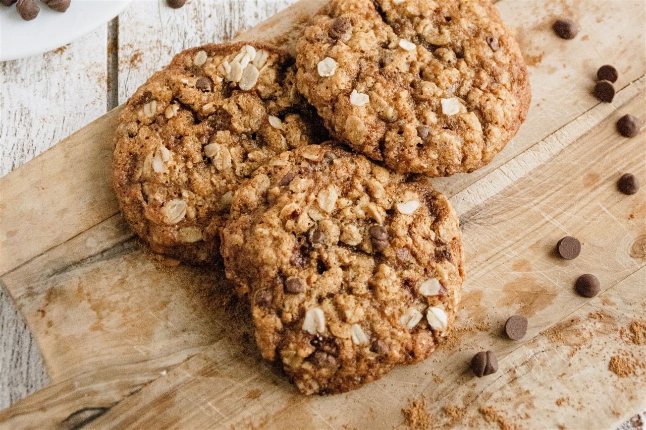 Cookies de aveia com gotas de chocolate empilhados sobre tábua de madeira
