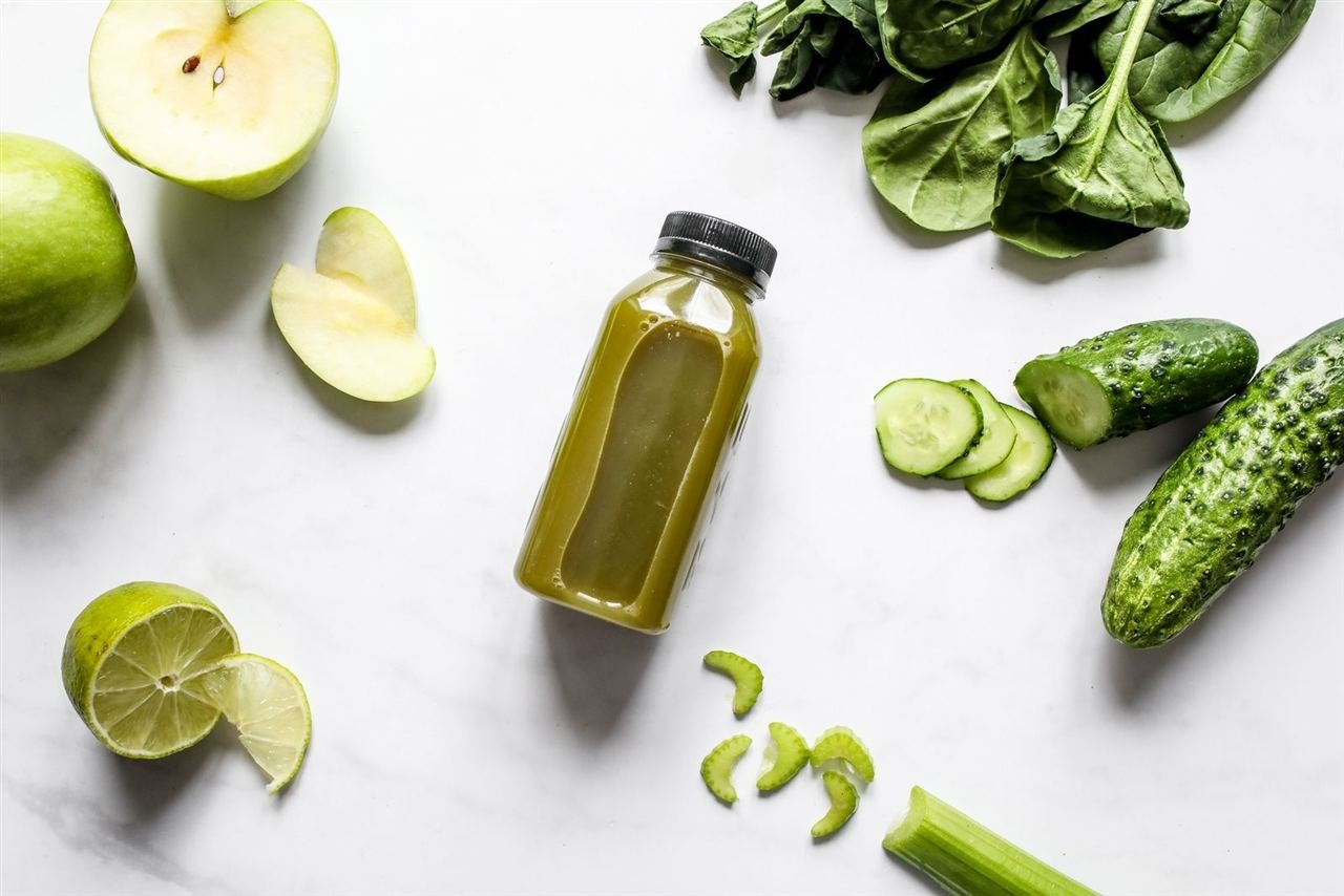 Copo de suco verde detox ao lado de vegetais frescos