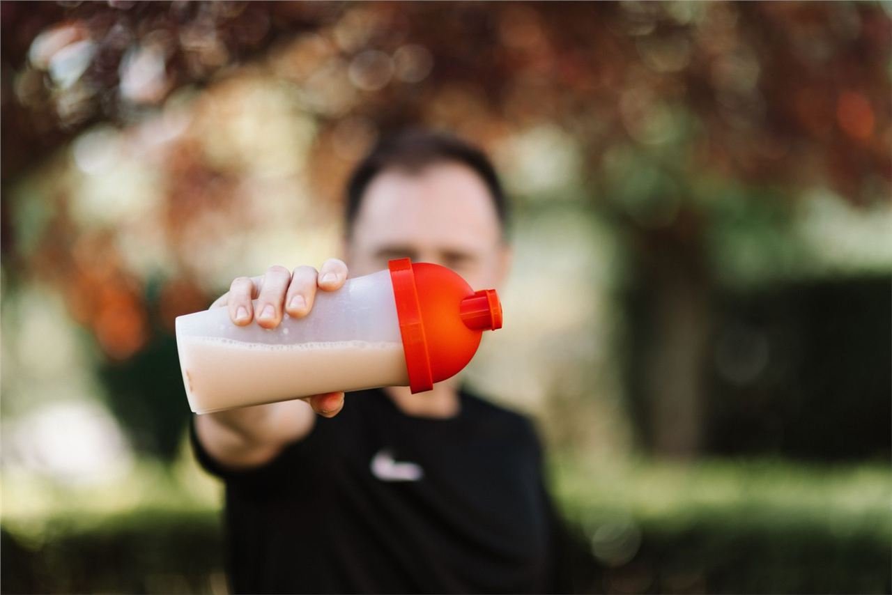 Whey protein em pó sendo despejado em coqueteleira