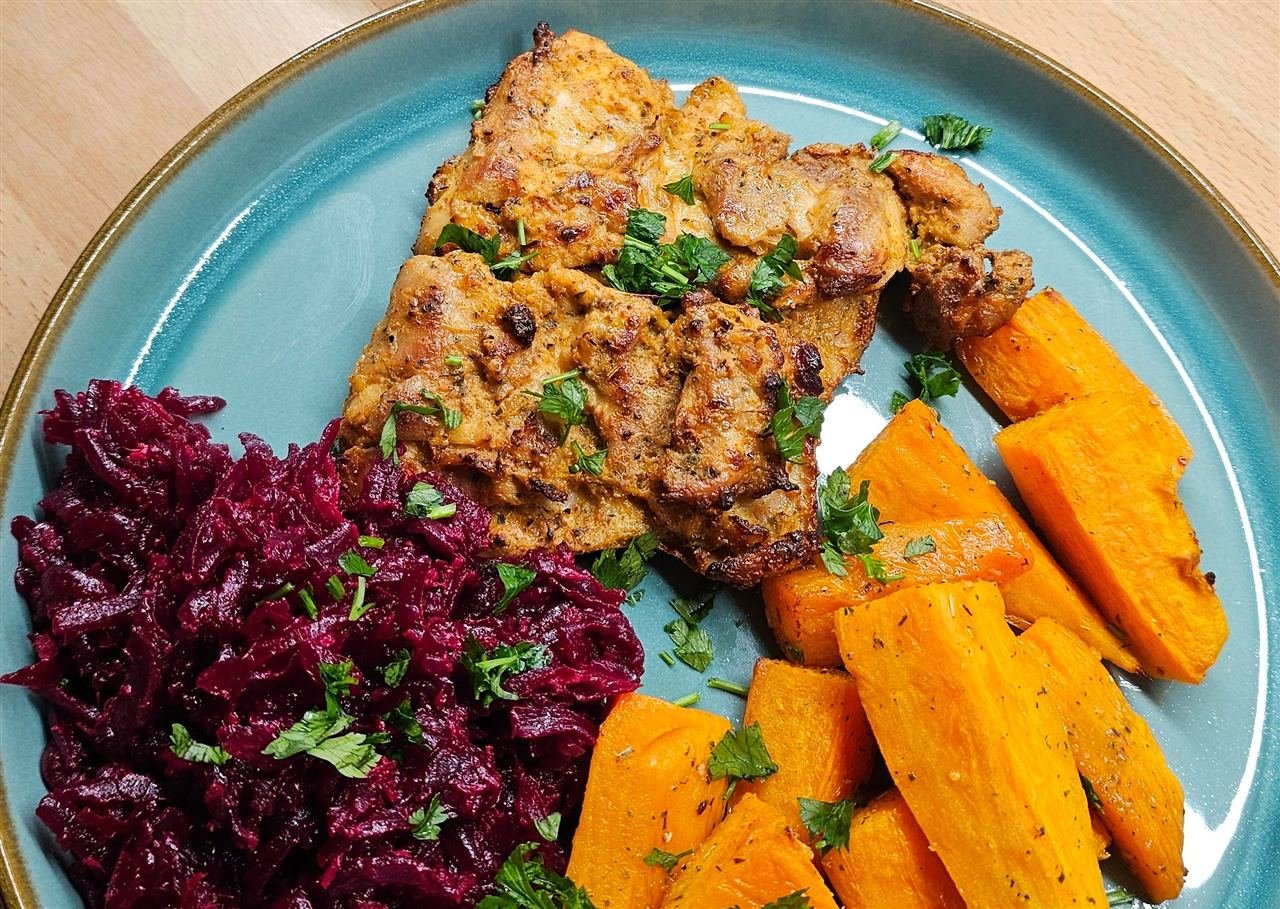 Frango grelhado servido com batata-doce assada e couve-roxa em prato