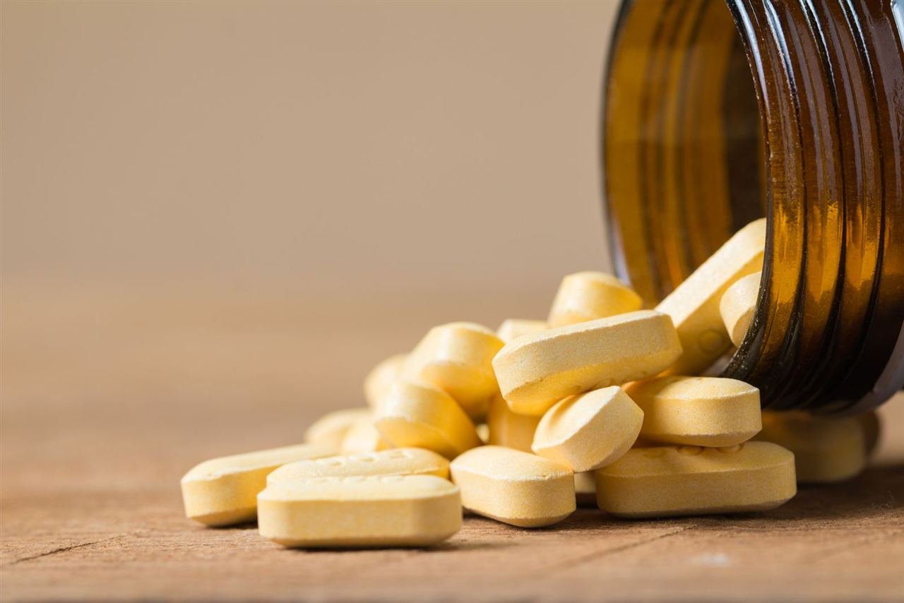 Frasco de suplemento de vitamina D próximo a uma janela iluminada pelo sol