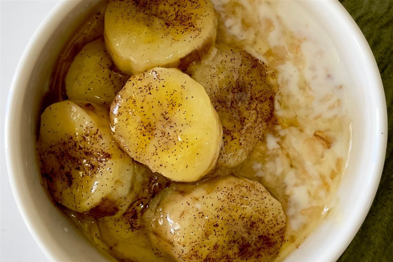 Tigela de mingau de aveia coberto com fatias de banana caramelizada e canela