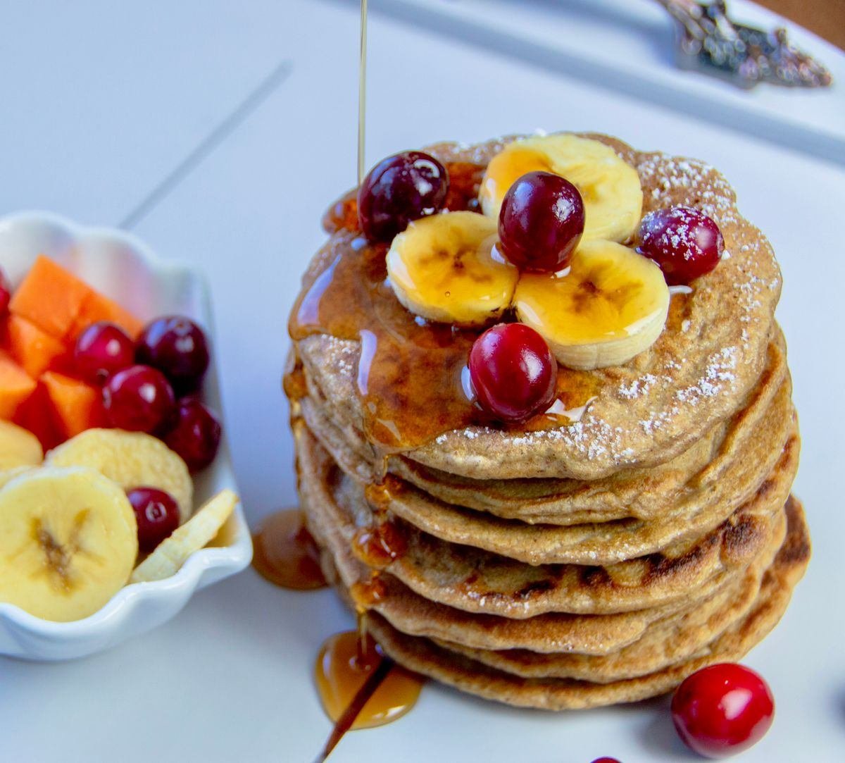Pilha de panquecas de banana e aveia com calda e frutas vermelhas