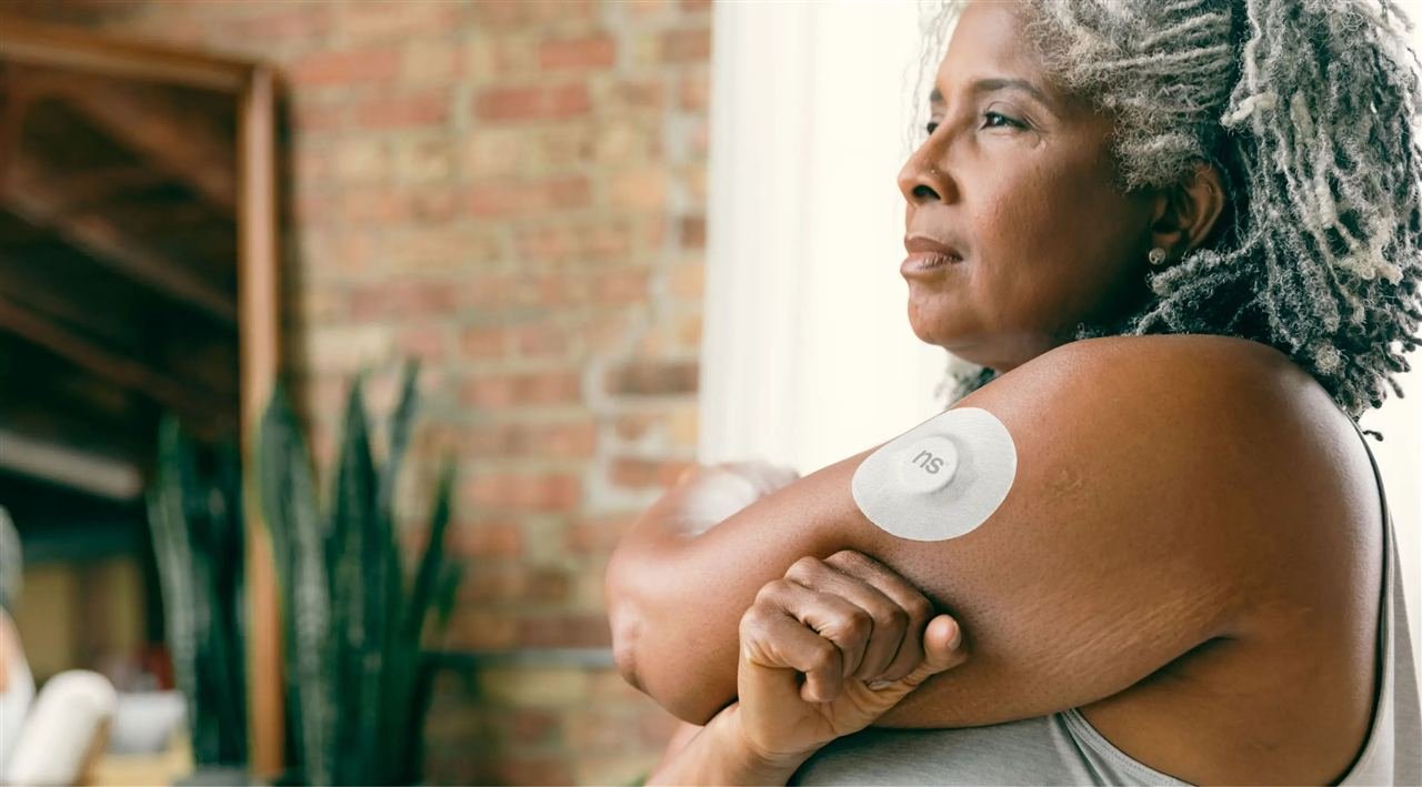 Mulher com sensor de monitor contínuo de glicose adesivo visível no braço