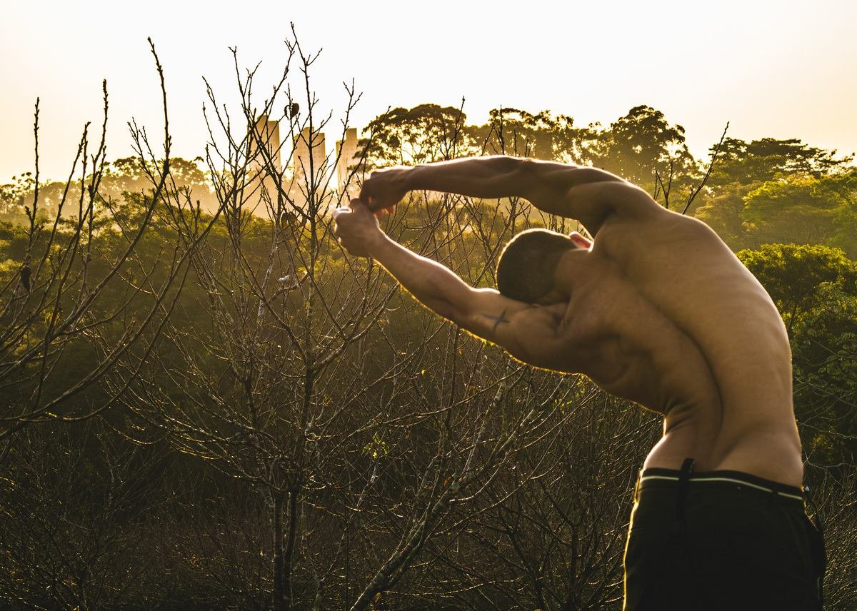 Homem se alongando ao ar livre durante o nascer do sol, treino matinal